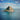 green and brown rock formation on blue sea under blue and white cloudy sky during daytime