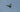 a fighter jet flying through a cloudy blue sky