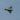a fighter jet flying through a cloudy blue sky