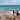 Waves crash on a beach with wooden posts.