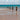 Wooden posts stand in the ocean, with waves.